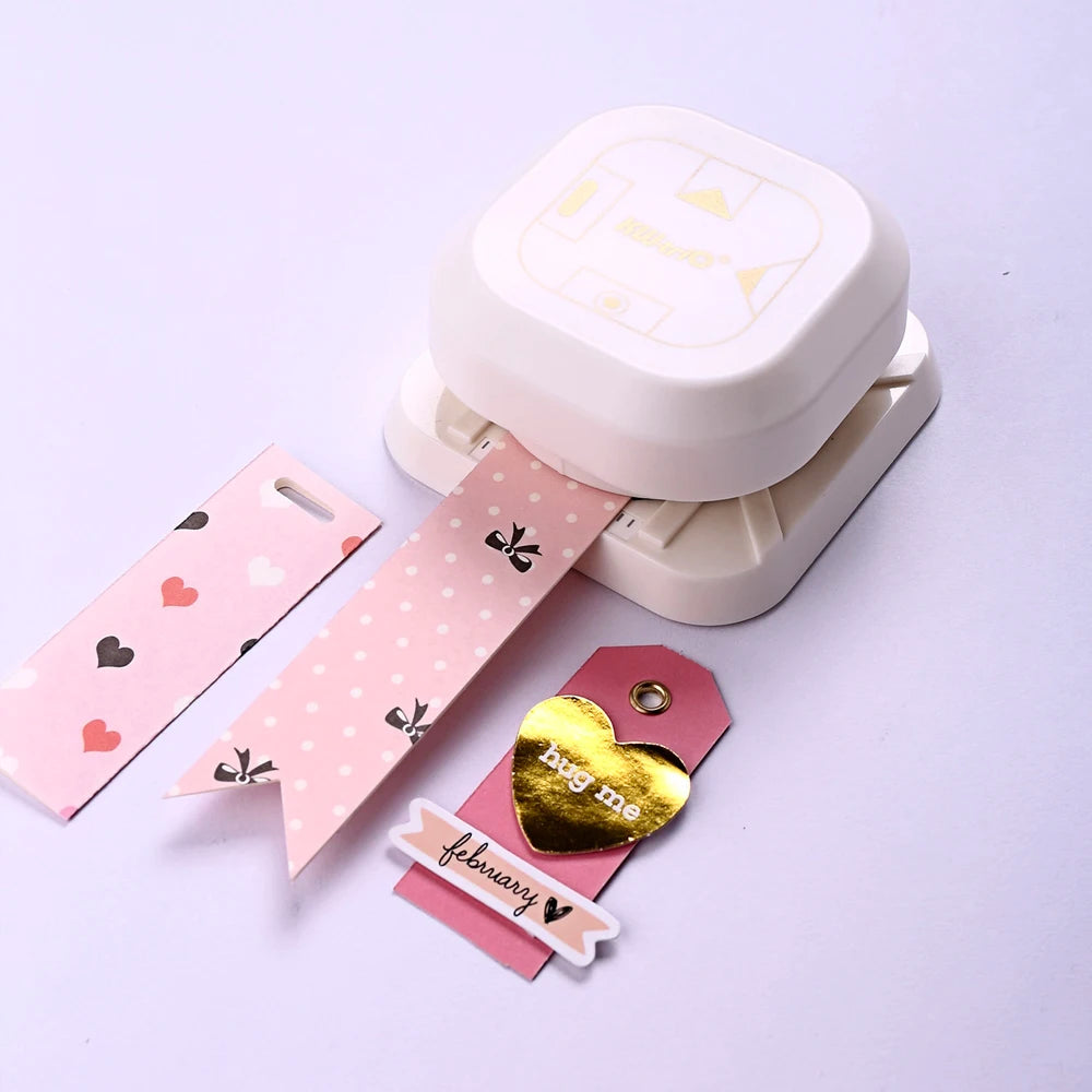 A white crafting tool set featuring a punch corner rounder and various tags with hearts and other designs.