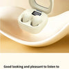 White mini Bluetooth earphones with a protective case resting on a beige surface.