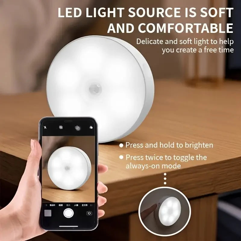 A hand holds a smartphone displaying a soft LED light source illuminating a cabinet or wardrobe interior.