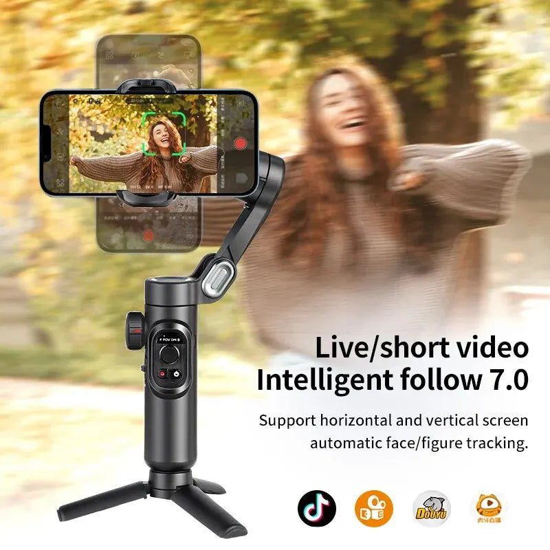 A black 3-axis gimbal stabilizer is shown with a smartphone recording in an outdoor setting.