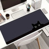 A dark gray cat silhouette mouse pad is placed on a white desk next to a computer monitor and stationery.