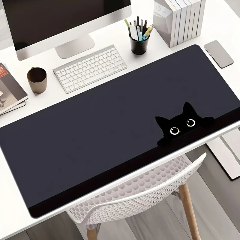 A dark gray cat silhouette mouse pad is placed on a white desk next to a computer monitor and stationery.