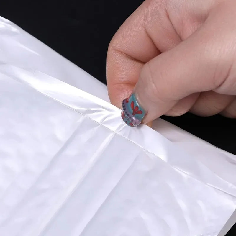 Une main place une petite autocollant en forme de cœur coloré sur une enveloppe blanche rembourrée.