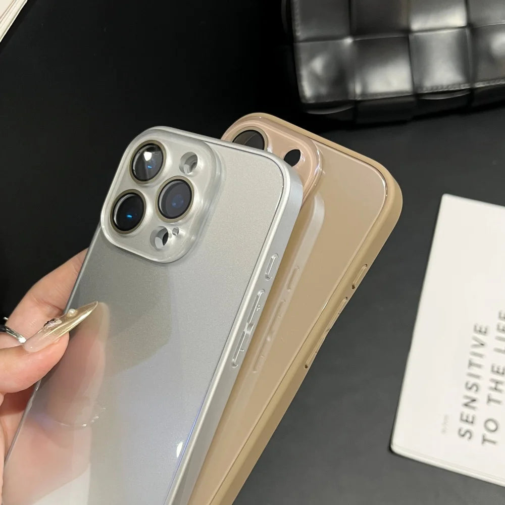 A hand holds a silver iPhone with a clear protective case next to a beige iPhone, set against a dark background.
