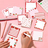 A collection of pink and red strawberry-themed self-stick memo notes and a pink spiral notebook being written in.