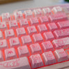 A close-up view of a pink PBT translucent keycap set for mechanical keyboards.