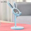 A light blue rabbit-shaped mobile phone stand with a mesh design is shown on a pink surface.