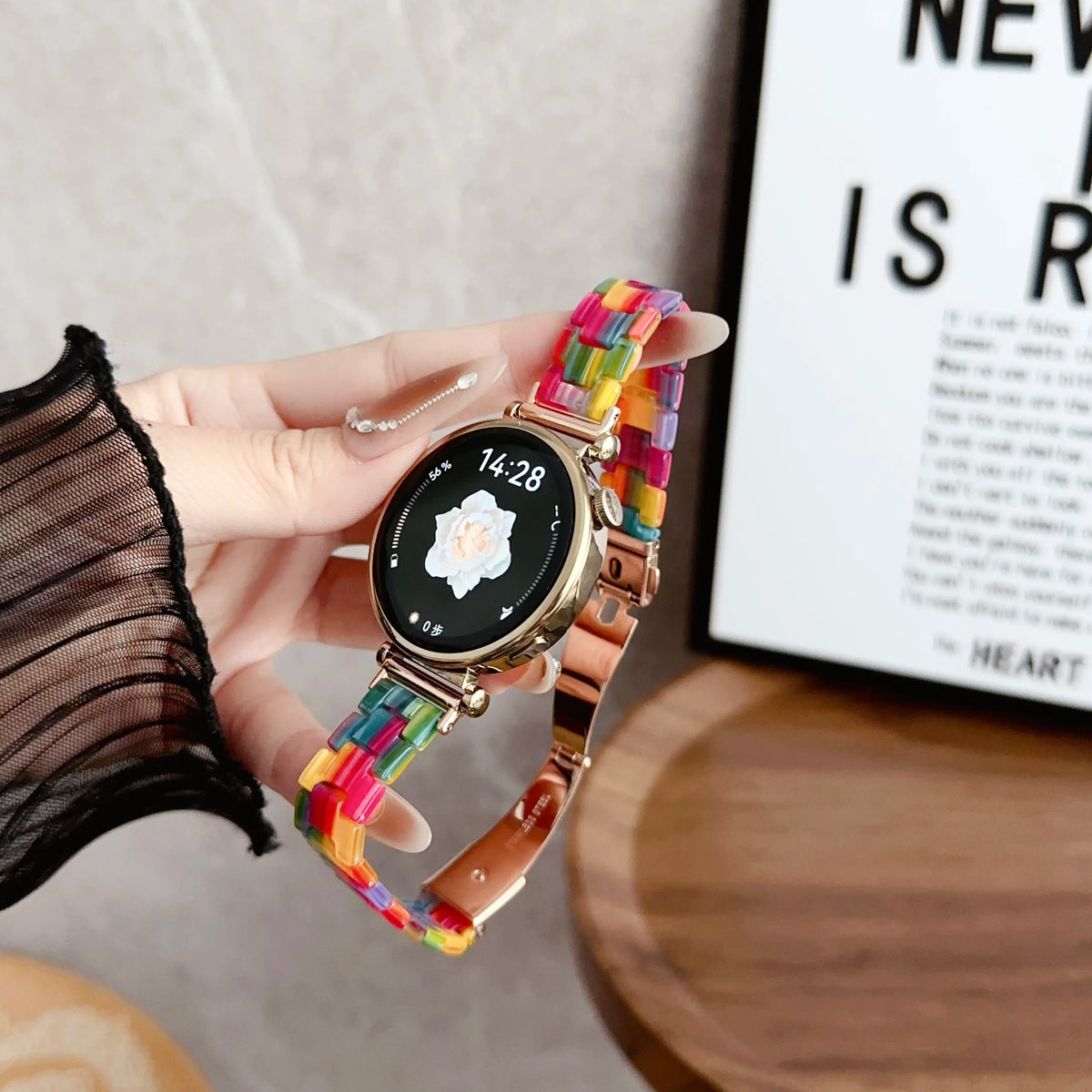 A hand holds a resin beaded watch with a floral design on the face and a multicolored beaded band.