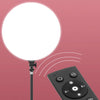 A round white LED ring light with a black base and control panel is shown against a pink background.