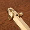 A close-up of a brass bolt-action ballpoint pen showing the barrel and a gold-colored metal ring.