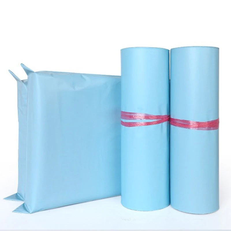 Three rolled light blue reusable waterproof poly shipping bags standing next to a flat bag.