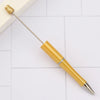 A gold-colored DIY beadable pen with a silver band and a pointed tip resting on a white surface.