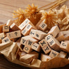 A pile of vintage wooden stamp seals and alphabet blocks resting on crumpled brown paper.