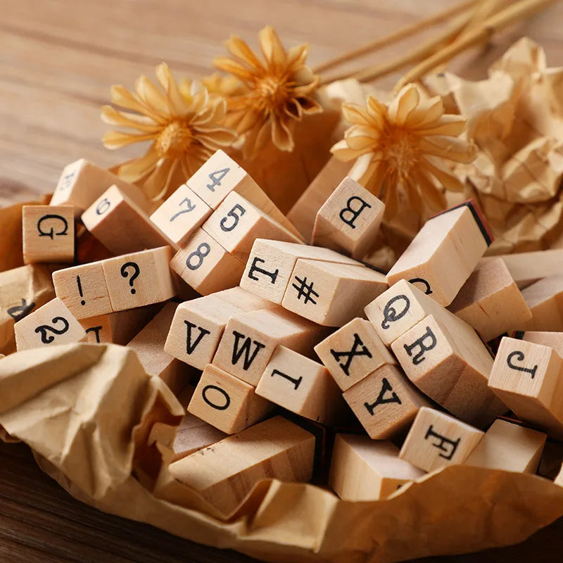 A pile of vintage wooden stamp seals and alphabet blocks resting on crumpled brown paper.