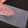 A hand is pressing through a sheet of transparent bubble wrap used for padding or shipping.