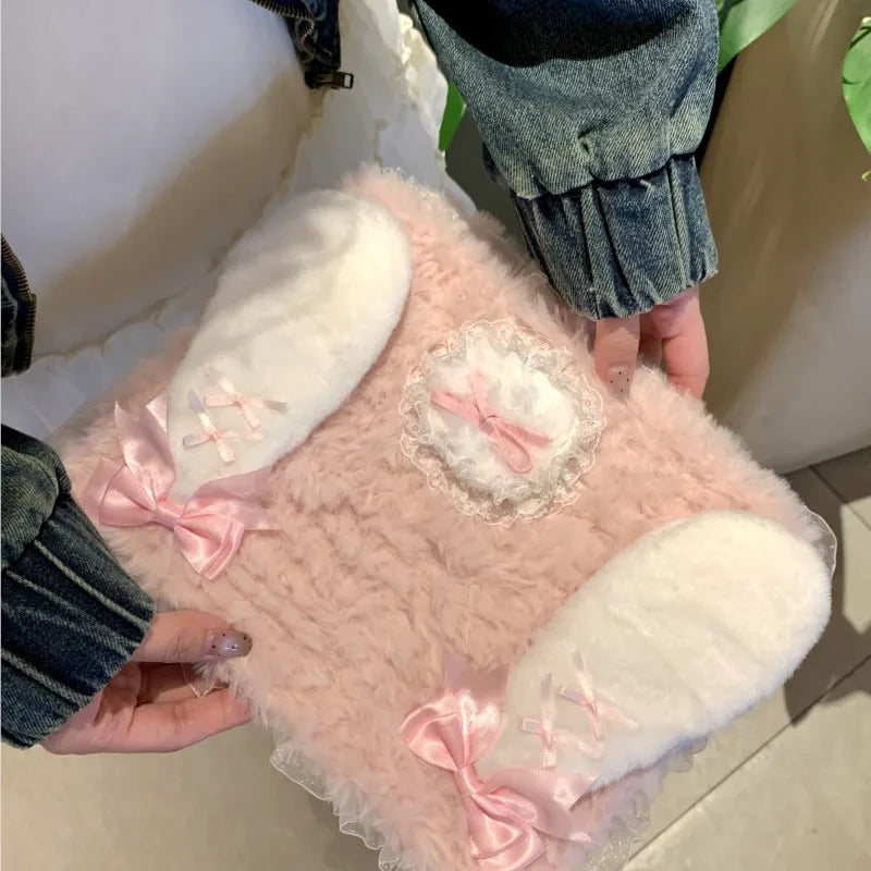 A pink rabbit plush case with white and pink accents is shown being held by a person.