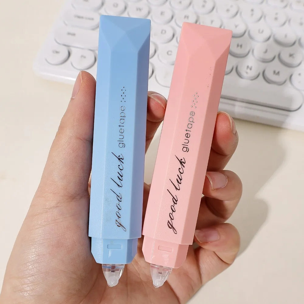 A hand holds a pink gradient double-sided tape pen labeled good luck gluetape.