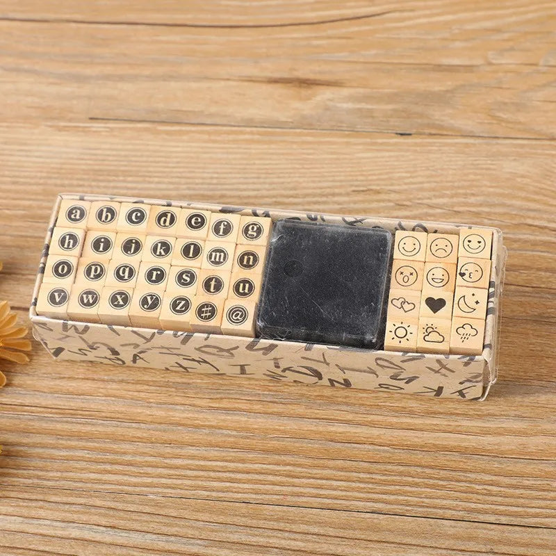 A rectangular wooden stamp seal set featuring alphabet letters and symbols in a light wood tone with a dark square stamp.