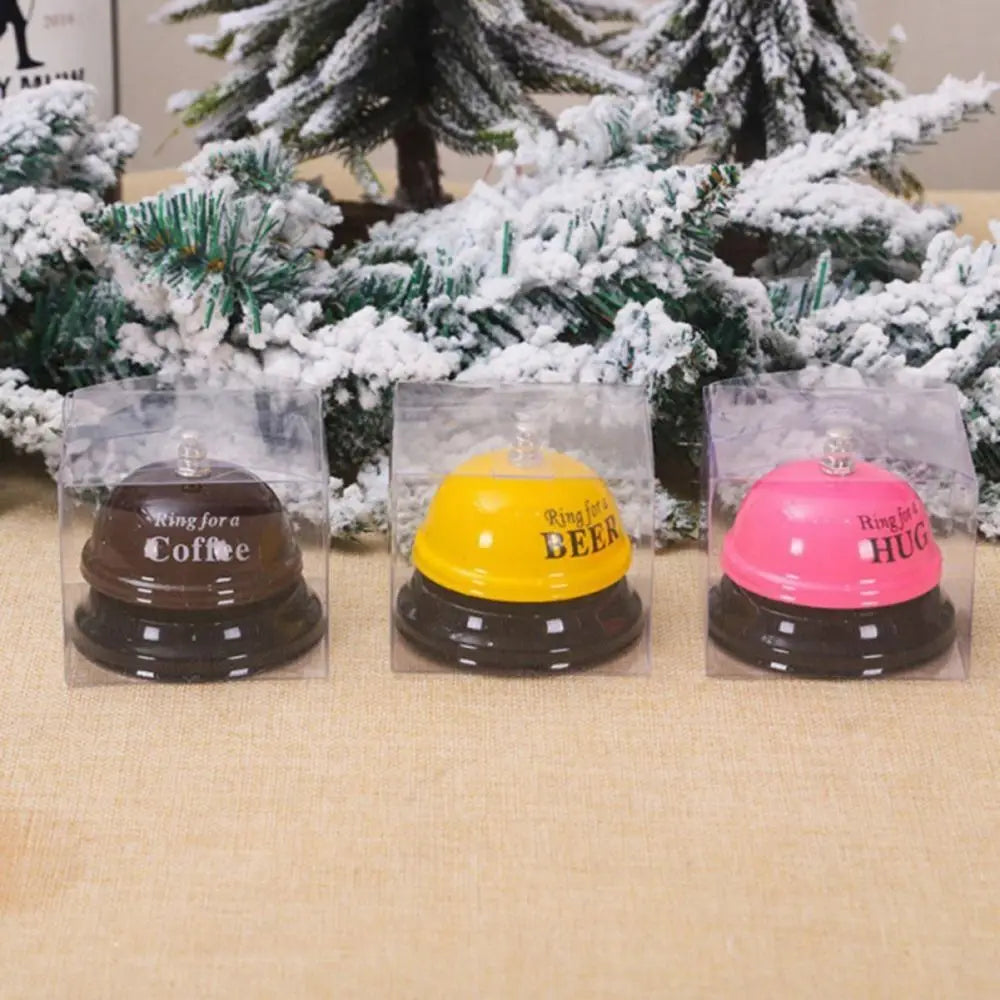 Three clear plastic packages containing metal service bells for coffee, beer, and hug.