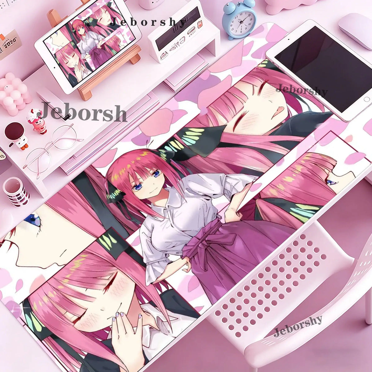 A pink anime character illustration on a mouse pad and desk mat with various stationery items.