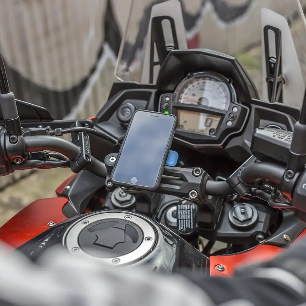 A close-up view of a motorcycle dashboard showing a mounted smartphone and an instrument cluster.