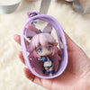 A hand holds a mini clear bag with a purple-haired anime character keychain inside.