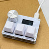 A white electronic device with a silver switch and several white square switches is shown on a brown surface.
