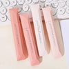 A set of pink gradient double-sided tape pens lying on a light surface next to a white keyboard.