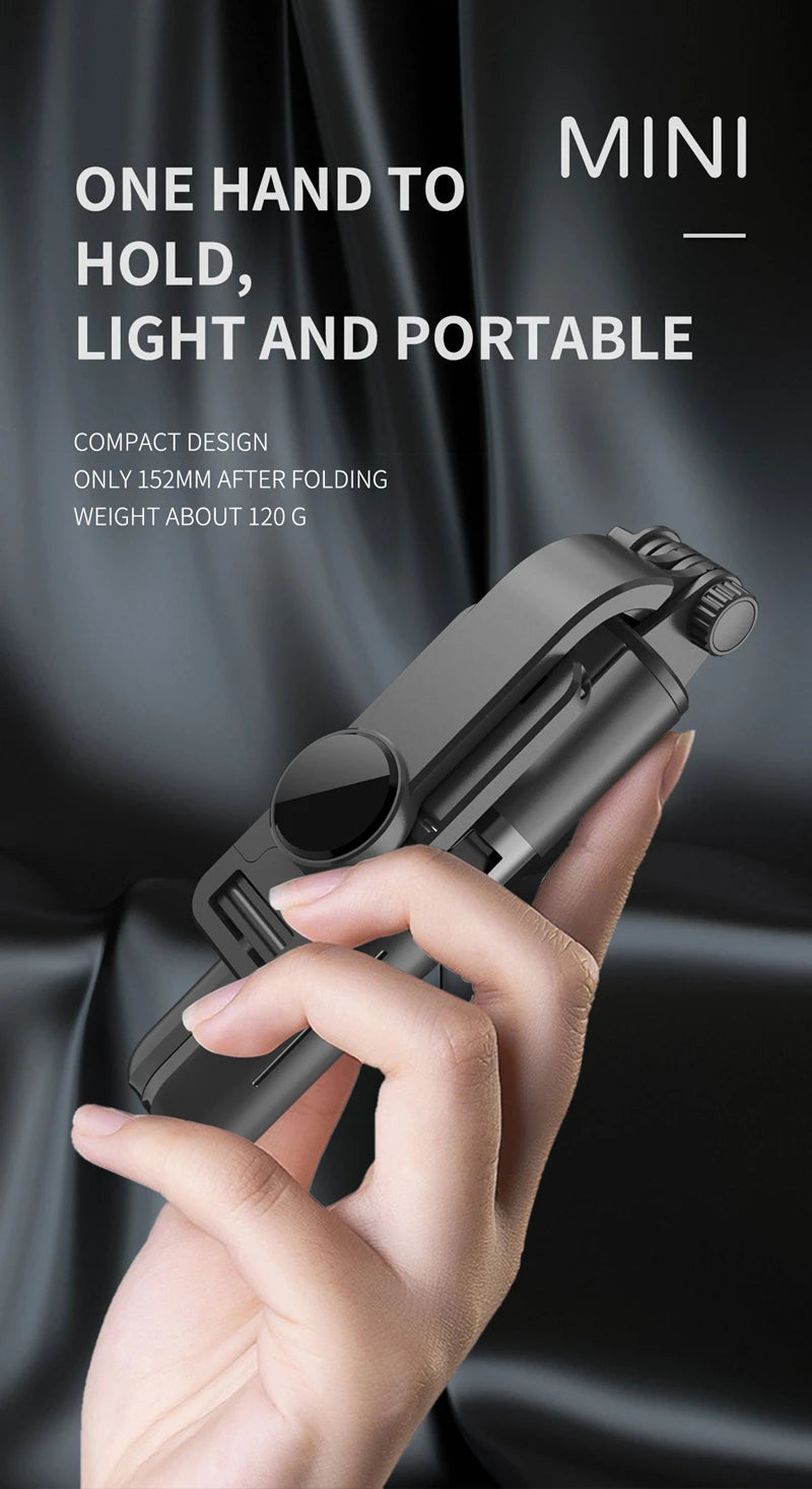 A hand holds a compact mini Bluetooth selfie stick with an LED light and tripod stand against a dark background.