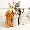 A collection of adorable plush dog toys in various colors and breeds sitting inside a white wire pet crate.