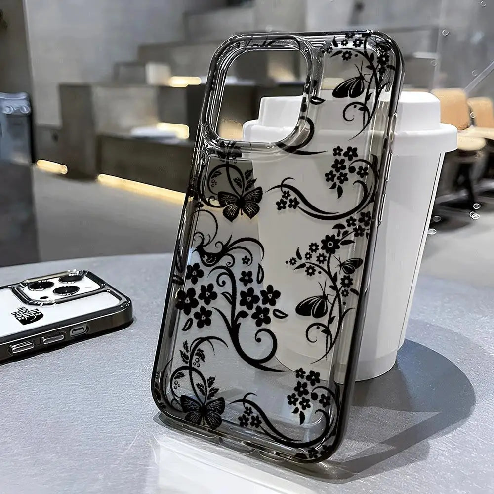 A clear phone case with a black floral pattern is displayed next to a white bottle.
