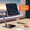 A black adjustable multi-angle tablet and phone stand is placed on a wooden desk next to a notebook.