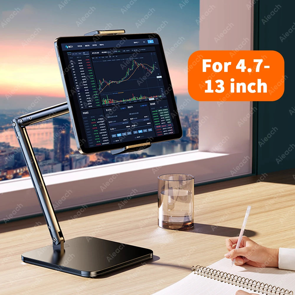 A black adjustable multi-angle tablet and phone stand is placed on a wooden desk next to a notebook.