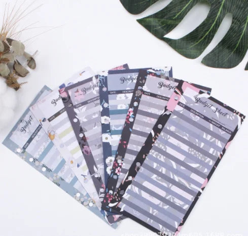 A stack of A6 budget planner sheets with envelope pockets and expense sheets in various pastel colors