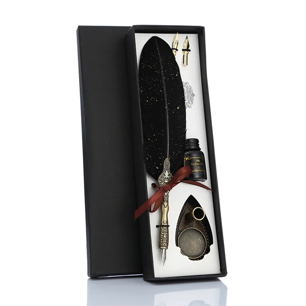 A black gift box contains a feather dip pen set with gold accents and a dark feather.