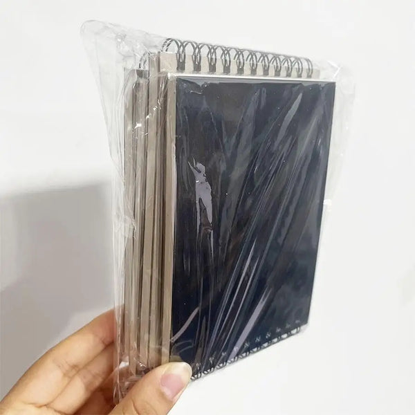 A clear plastic package containing a set of sketchbooks with dark covers and light-colored paper inside.