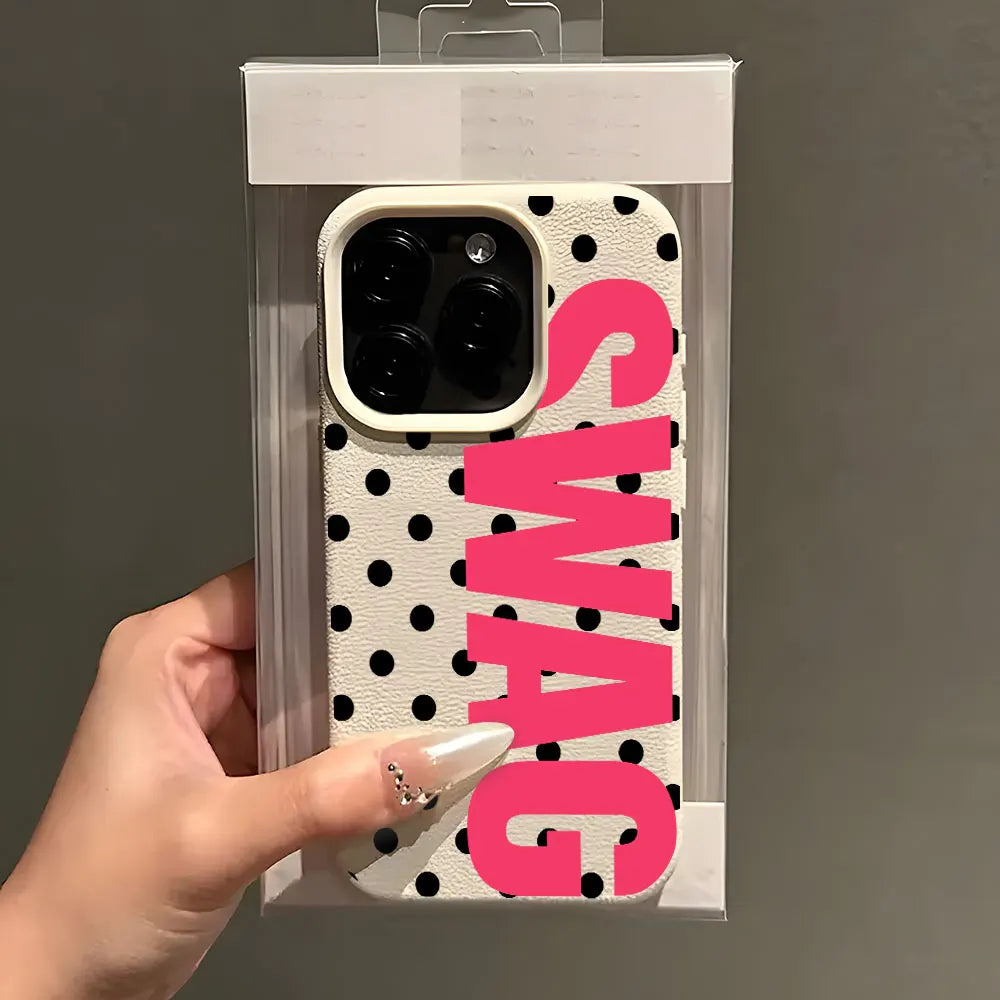 A pink polka dot phone case with the word SWAG printed on it, shown being held by a hand.