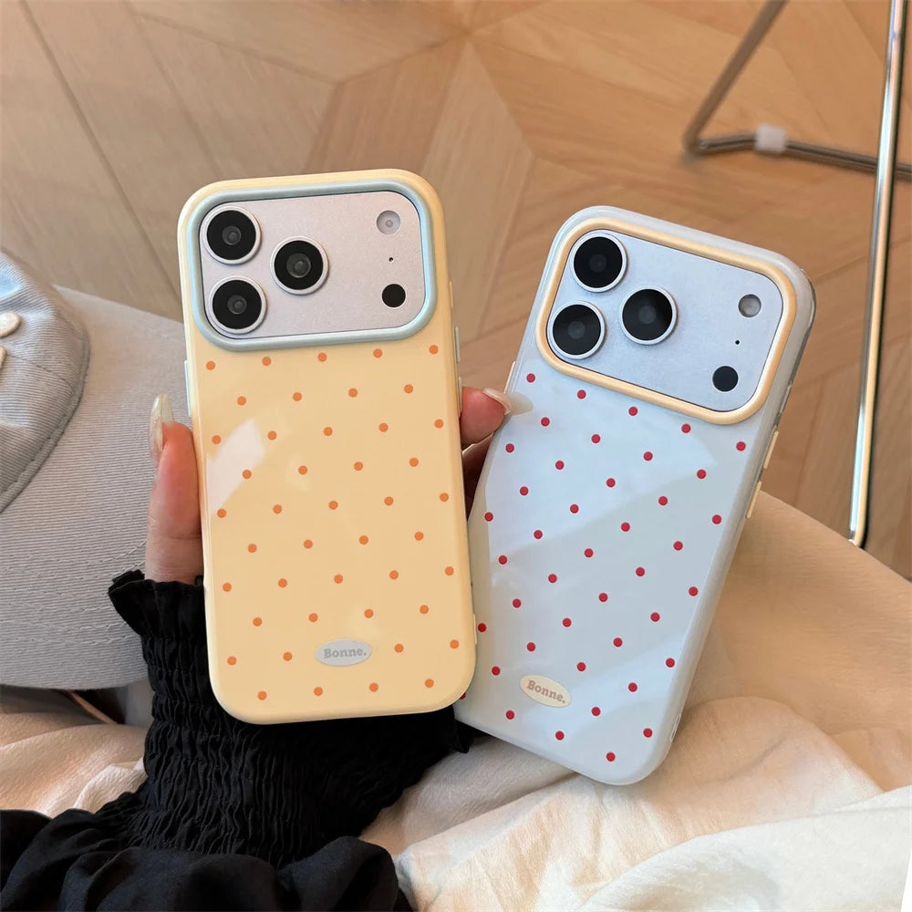 A hand holds a yellow candy polka dot shockproof phone case for an iPhone against a light background.