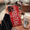 A red vintage license plate phone case for an iPhone is held by a person in a dark sleeve.