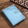 A light blue A5 retro leather notebook with a gold-toned clasp resting on a wooden surface.