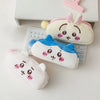 A collection of Chiikawa plush pencil cases and organizers in white, pink, and blue colors resting on a white desk.