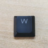 A close-up view of a dark blue mechanical keyboard keycap with the letter W on it.