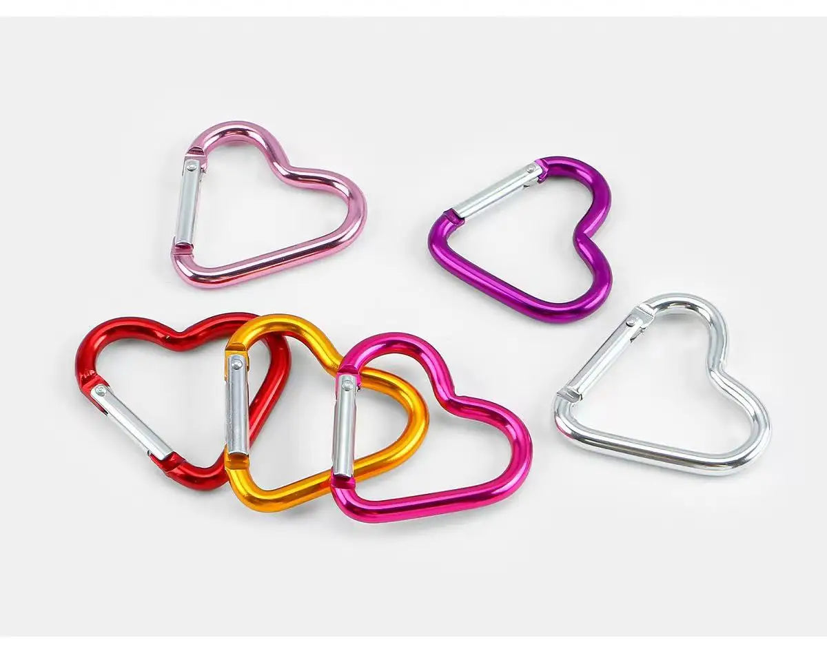 A set of five colorful heart-shaped spring clasps and carabiner keychains in various shades of pink, purple, and gold.