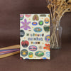 A colorful sticker book featuring fruit icons, such as a purple plum and orange slices, for crafting and journaling.