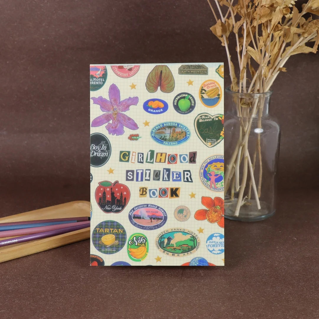 A colorful sticker book featuring fruit icons, such as a purple plum and orange slices, for crafting and journaling.