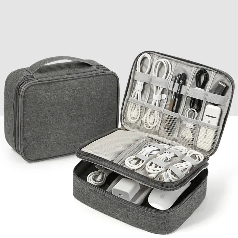 A gray travel cable organizer bag with an open compartment showing various electronic cables and accessories.