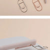 A collection of elegant metal pen clips in various rose gold and silver tones arranged on a light background.