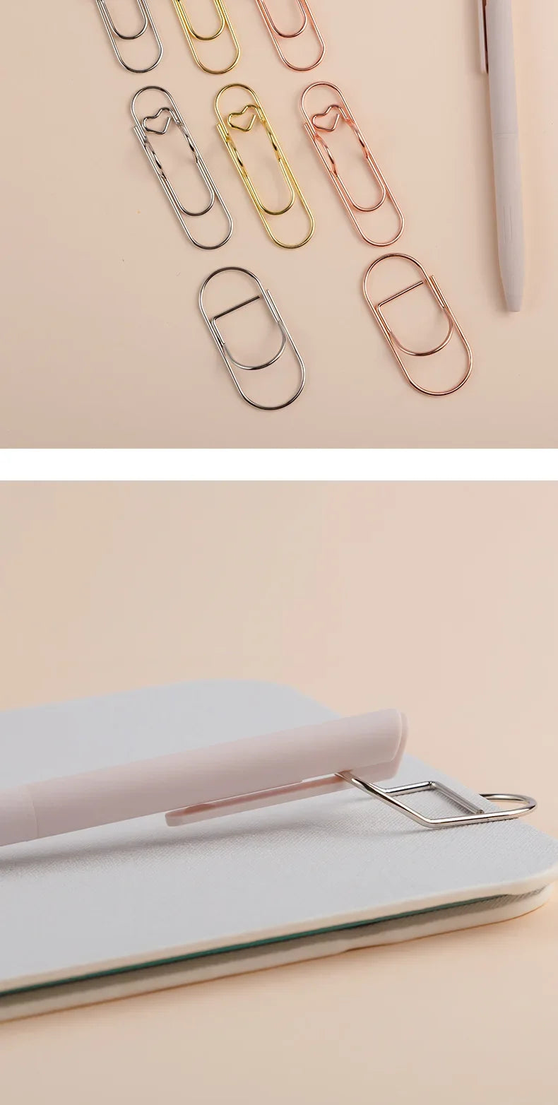 A collection of elegant metal pen clips in various rose gold and silver tones arranged on a light background.