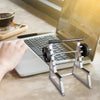 A silver barbell rack desk pen holder organizer is placed next to an open laptop on a light surface.