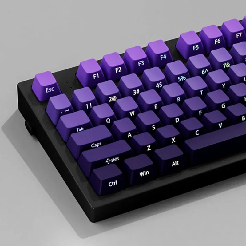 A close-up view of a mechanical keyboard with purple gradient keycaps and black casing.